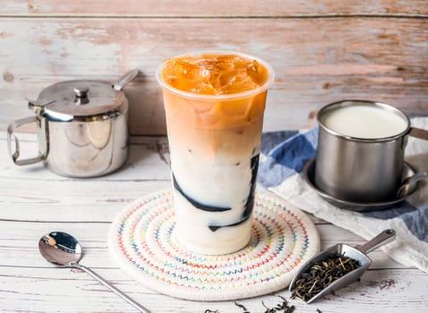 Iced Grass jelly fresh milk tea with sugar pot and spoon served in disposable glass isolated on table side view of hong kong tea photo