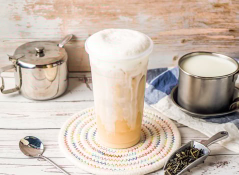 Iced Tieguanyin with Fresh Milk Tea or Tie guan yin with sugar pot and spoon served in disposable glass isolated on table side view of hong kong tea photo