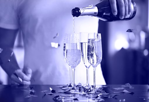 Champagne Flutes In Sparkle Background with golden confetti. Man pouring sparkle wine photo