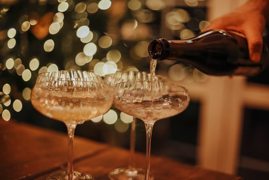 New Years Eve celebration. Man pouring champagne into glasses standing on table with festive Christmas dinner photo