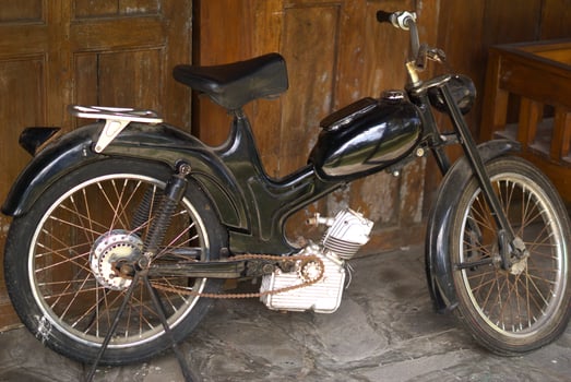 old fashioned motorcycle parked in front of wooden building photo