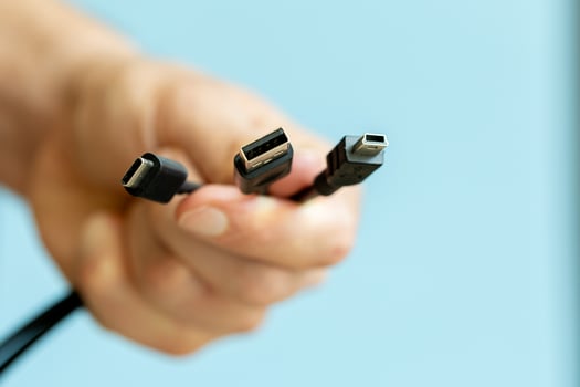 a person holding different usb cable on a plain blue background photo