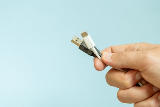 a person holding different usb cable on a plain blue background photo