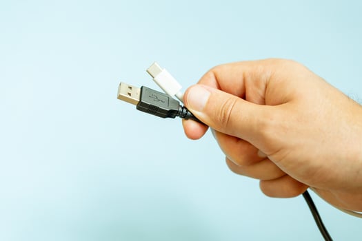a person holding different usb cable on a plain blue background photo