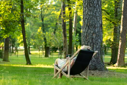 a woman is sitting in a lawn chair in the middle of a forest photo