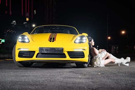 Hanoi, Vietnam - 26 Jun 2024 Beautiful young woman wearing bikini with Porsche 718 Boxster parked on the street during fashion photoshoot. photo