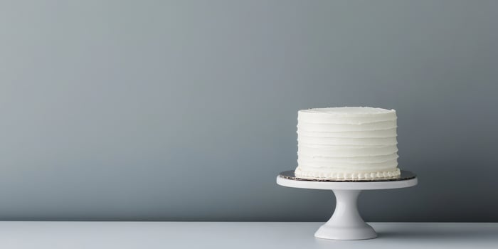 A simple yet elegant white birthday cake on a lovely stand makes the perfect centerpiece for any celebration. Its minimalistic design enhances its charm, making it a delightful treat for all photo