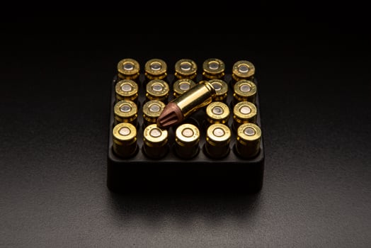 Pistol cartridges 9 mm on a smooth glossy surface with reflections. Ammunition for pistols and PCC carbines on a dark back. photo