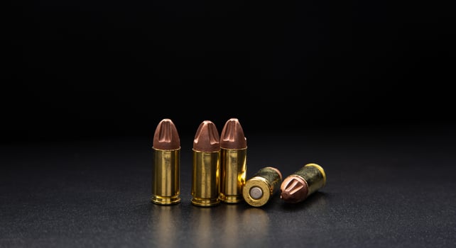 Pistol cartridges 9 mm on a smooth glossy surface with reflections. Ammunition for pistols and PCC carbines on a dark back. photo