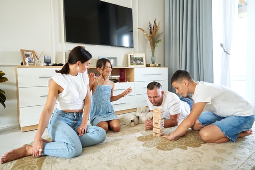 Family playing a jenga game on the floor in a bright living room during the afternoon photo