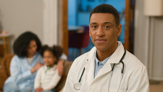 African American man doctor looking at camera smiling speech therapist pediatrician house call healthcare worker family mother and daughter help patient woman girl medicine visit recovery home room photo