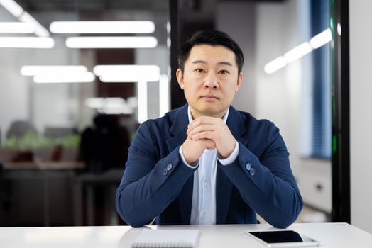 Portrait of a focused and confident businessman sitting at a meeting table in a contemporary office environment, with natural light illuminating the space. photo