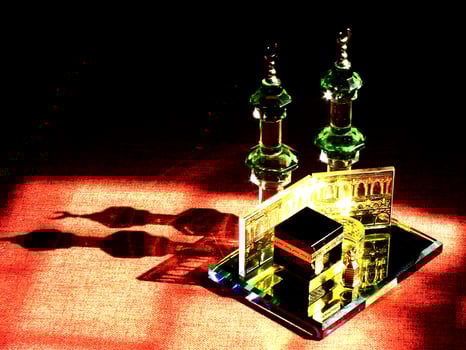 Small model of the Kaaba, the holy mosque of the Grand Mosque, Mecca, isolated on a dark background. There is sunlight coming performing an amazing shadow and shining reflection photo