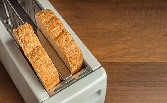 Rich and soft whole wheat bread in the toaster on wooden table background. Close-up photo. Space for text photo