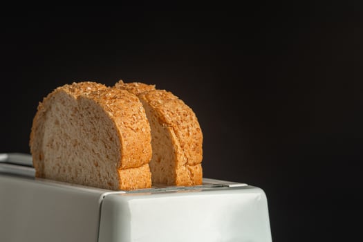 Rich and soft whole wheat bread in the toaster with a black background. Close-up photo. Space for text photo
