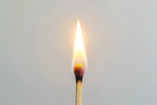 Single burning matchstick against a clean white background. Concept of ignition, heat, energy, simplicity, and minimalism. Copy space photo
