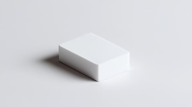 Simple white eraser resting on a clean surface, capturing natural light from above in a minimalistic setting photo
