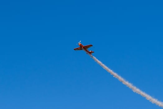 A small plane flying through the sky with smoke trailing behind it photo