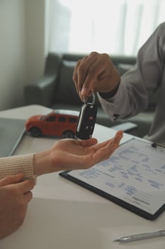 Young man receives a key from car salesman. After agreeing to a contract for rent or sale of a car at workshop, loan car, insurance, sale, buying car and finance concept. photo