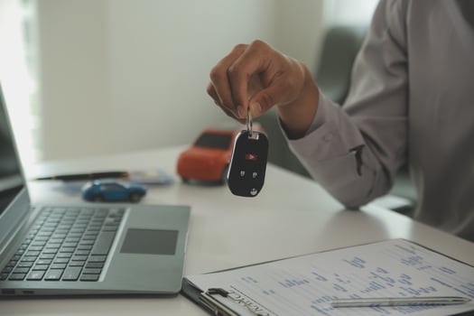 Young man receives a key from car salesman. After agreeing to a contract for rent or sale of a car at workshop, loan car, insurance, sale, buying car and finance concept. photo