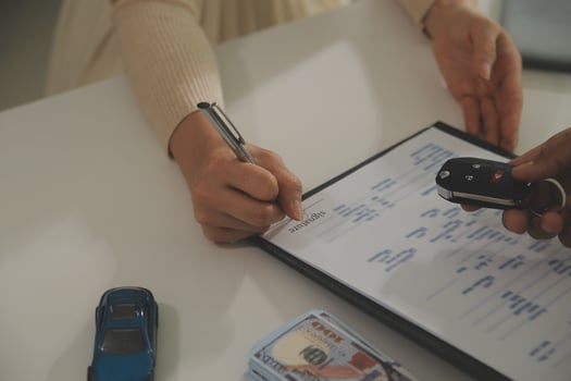 Young man receives a key from car salesman. After agreeing to a contract for rent or sale of a car at workshop, loan car, insurance, sale, buying car and finance concept. photo