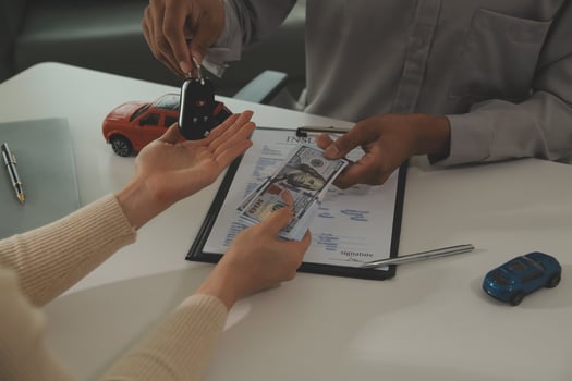 Young man receives a key from car salesman. After agreeing to a contract for rent or sale of a car at workshop, loan car, insurance, sale, buying car and finance concept. photo