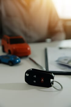 Young man receives a key from car salesman. After agreeing to a contract for rent or sale of a car at workshop, loan car, insurance, sale, buying car and finance concept. photo