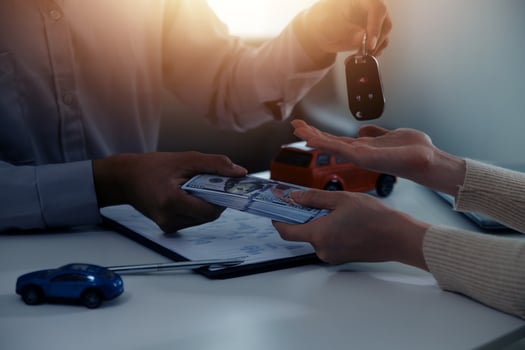 Young man receives a key from car salesman. After agreeing to a contract for rent or sale of a car at workshop, loan car, insurance, sale, buying car and finance concept. photo