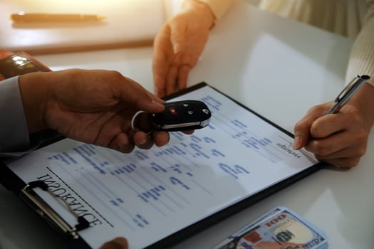 Young man receives a key from car salesman. After agreeing to a contract for rent or sale of a car at workshop, loan car, insurance, sale, buying car and finance concept. photo