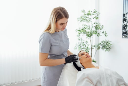 Female cosmetologist in transparent gloves makes an injection in the lower jaw of her client photo