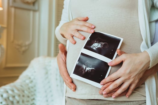 Family planning. Loving husband hugging his pregnant wife holding ultrasound scan in hands photo