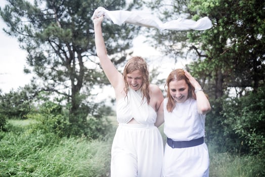 Two charming girls in white dresses are running in the summer rain. The young carefree women laugh and enjoy the rain. photo