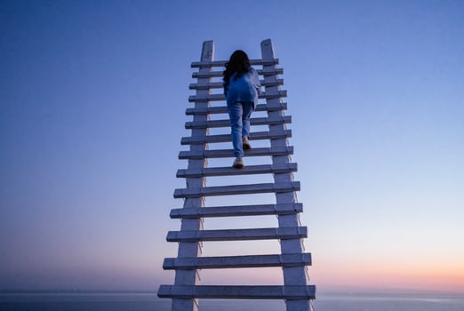 An attractive Asian woman is laughing and sitting at the top of a wooden staircase outdoors photo