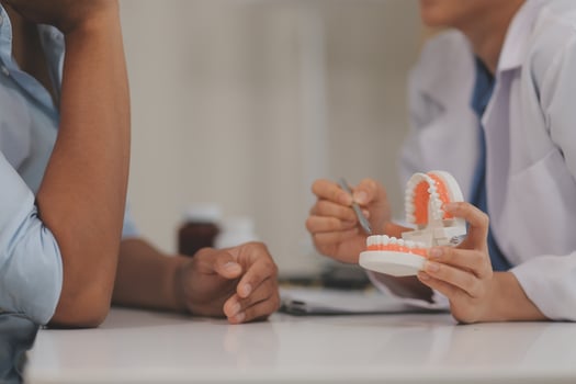 Dentist consultation - patient visit at the dental clinic office. Female dentist wearing dentures to explain teeth Recommend guidelines for orthodontics Dentist giving advice on patient's condition photo