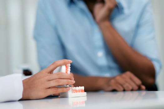 Dentist consultation - patient visit at the dental clinic office. Female dentist wearing dentures to explain teeth Recommend guidelines for orthodontics Dentist giving advice on patient's condition photo