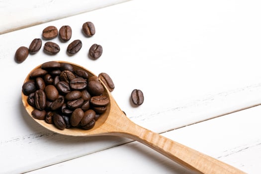 roasted coffee beans with wooden spoon on a white wooden background top view photo