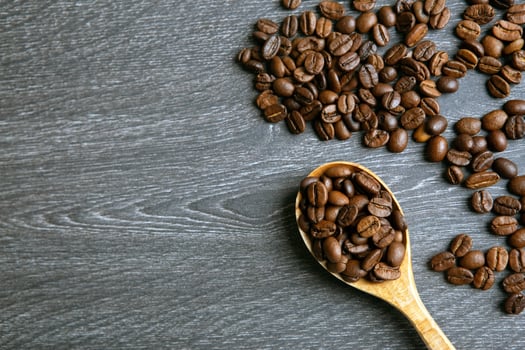 roasted coffee beans with wooden spoon on a wooden background top view photo