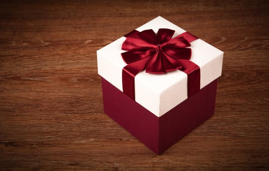 white box with red bow on a wooden background photo