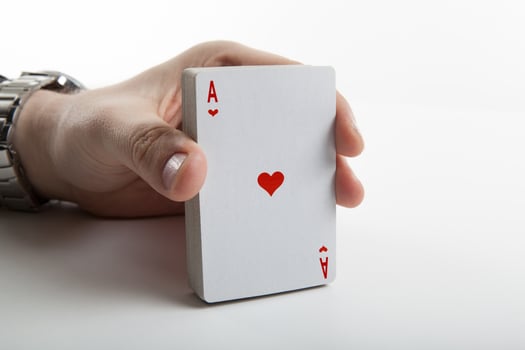Human hand holding the ace of hearts and a deck of cards photo