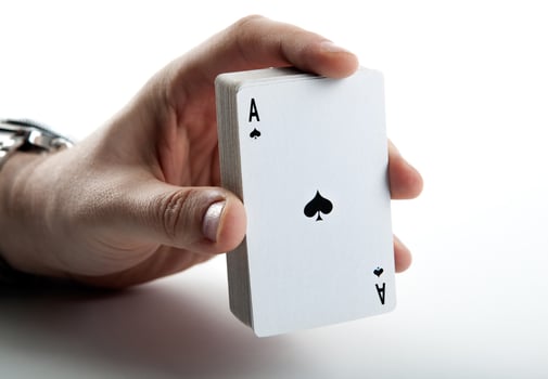 Human hand holding the ace of spades and a deck of cards photo