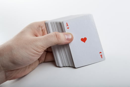 Human hand holding the ace of hearts and a deck of cards photo