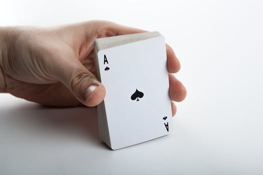 Human hand holding the ace of spades and a deck of cards photo