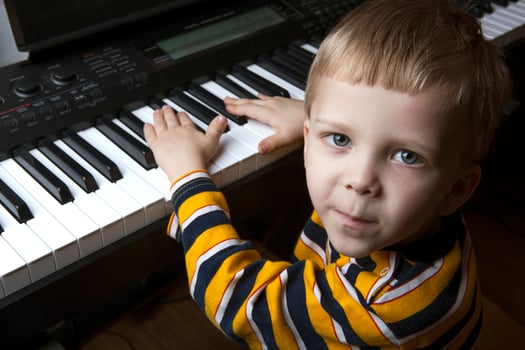 talented little boy sitting at the piano photo