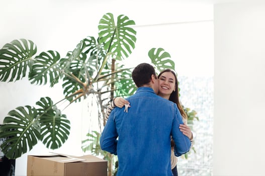 Happy couple with cardboard boxes hugging in new home photo