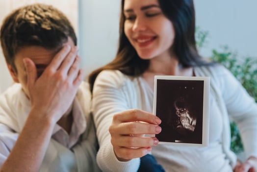 Young couple waiting for baby. Happy pregnant woman showing pregnancy ultrasound to husband photo