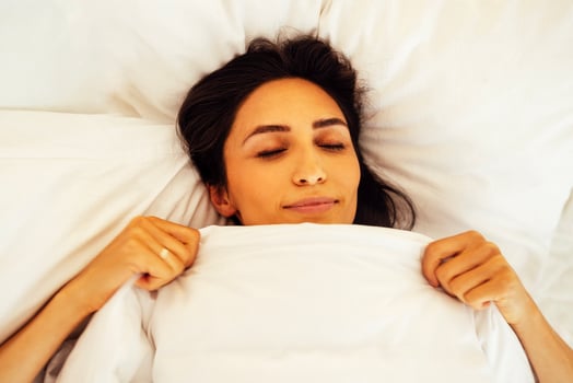 An attractive happy young woman is lying in bed with her eyes closed photo