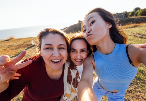 A group of young attractive multiethnic women take selfies and laugh outdoors photo