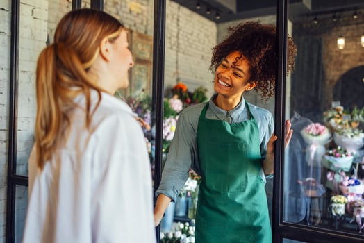 Happy black woman entrepreneur standing in plant store selling fresh flowers to client. photo