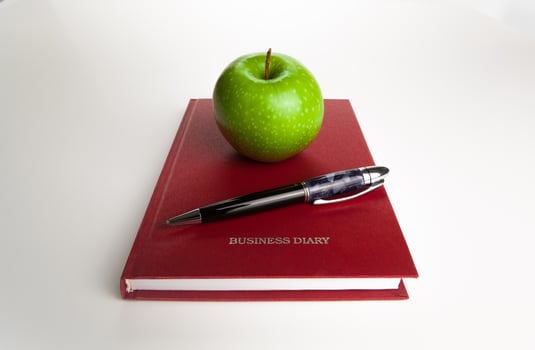 business diary with pen and green apple photo