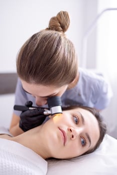 Doctor dermatologist examines skin of client face of beauty salon with a dermatological lens photo